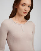 Woman wearing a beige long-sleeve shirt with buttons on a light gray background