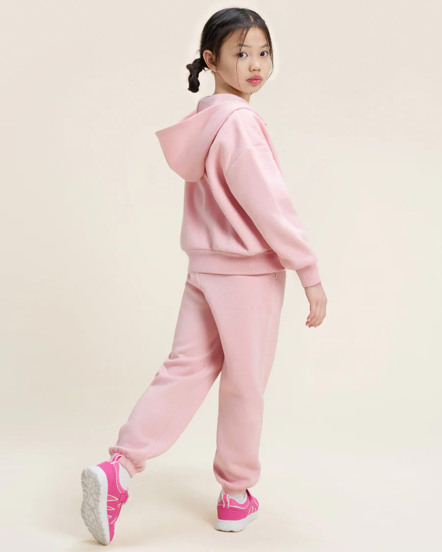 Child wearing a pink tracksuit on a beige background