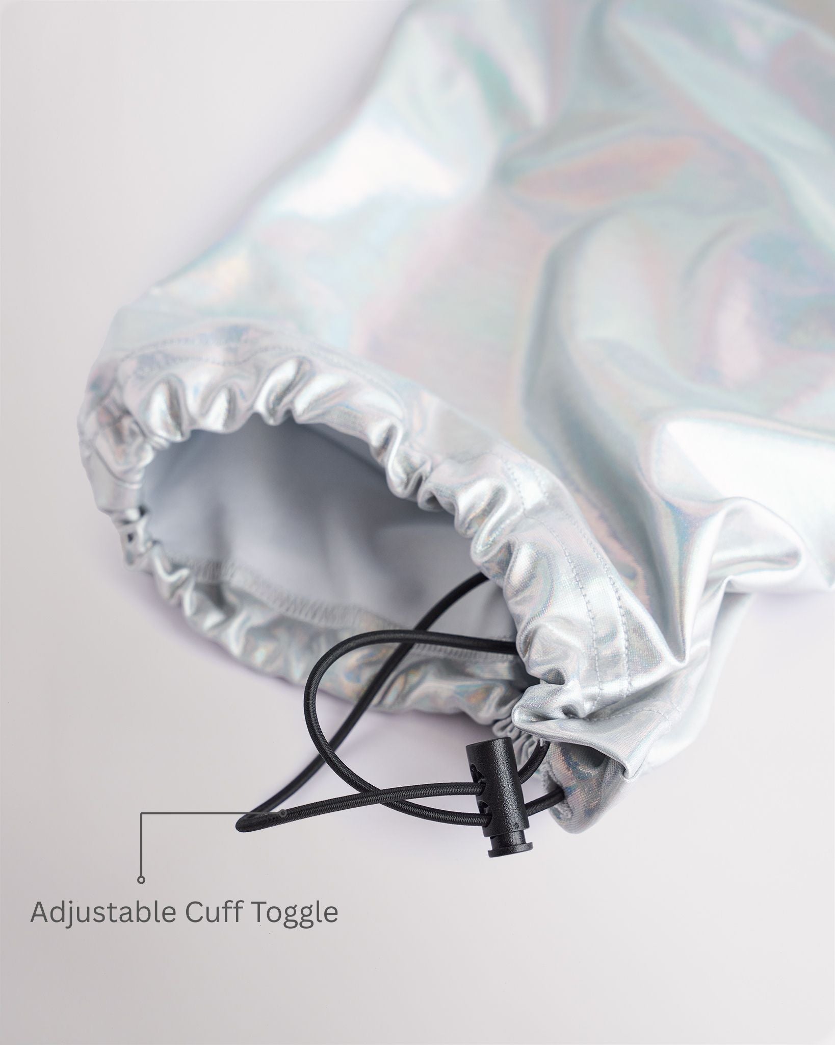 Close-up of holographic silver girls cargo pants showing the adjustable cuff toggle at the hem for switching between wide-leg and tapered jogger styling.