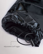 Close-up of patent black girls cargo pants showing the adjustable cuff toggle at the hem for switching between wide-leg and tapered jogger styling.