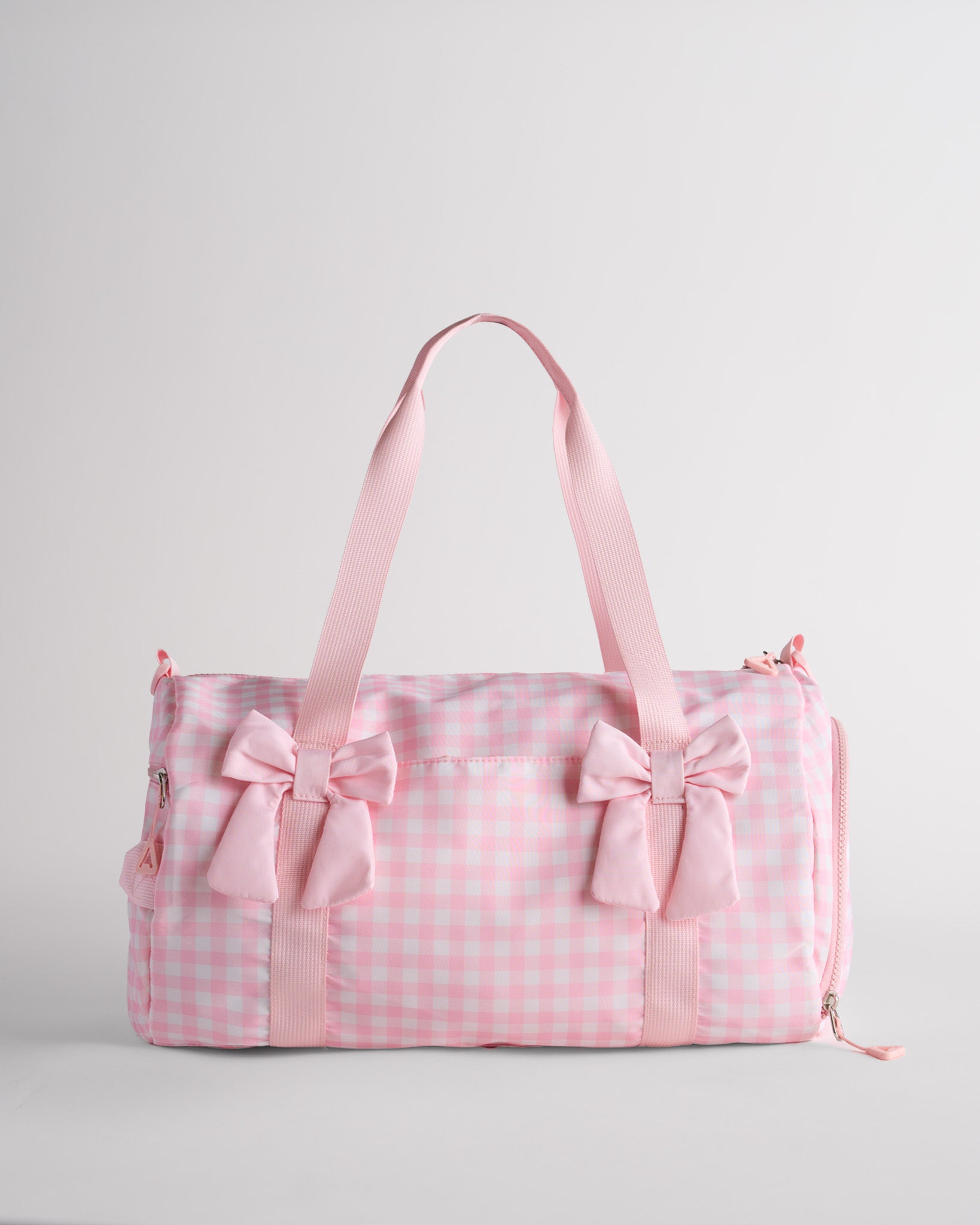 Kids pink gingham duffle bag with bows and spacious main compartment designed for sports and dance essentials.