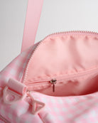 Pink gingham duffle bag interior with zip pocket and organized storage compartments for small items.