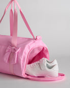 Kids taffy pink duffle bag with side shoe compartment holding sneakers, ideal for separating shoes from clothes.