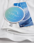 Close-up of white sunscreen face mask showing UPF 50+ built-in protection tag, smooth fabric, and Stelle logo.