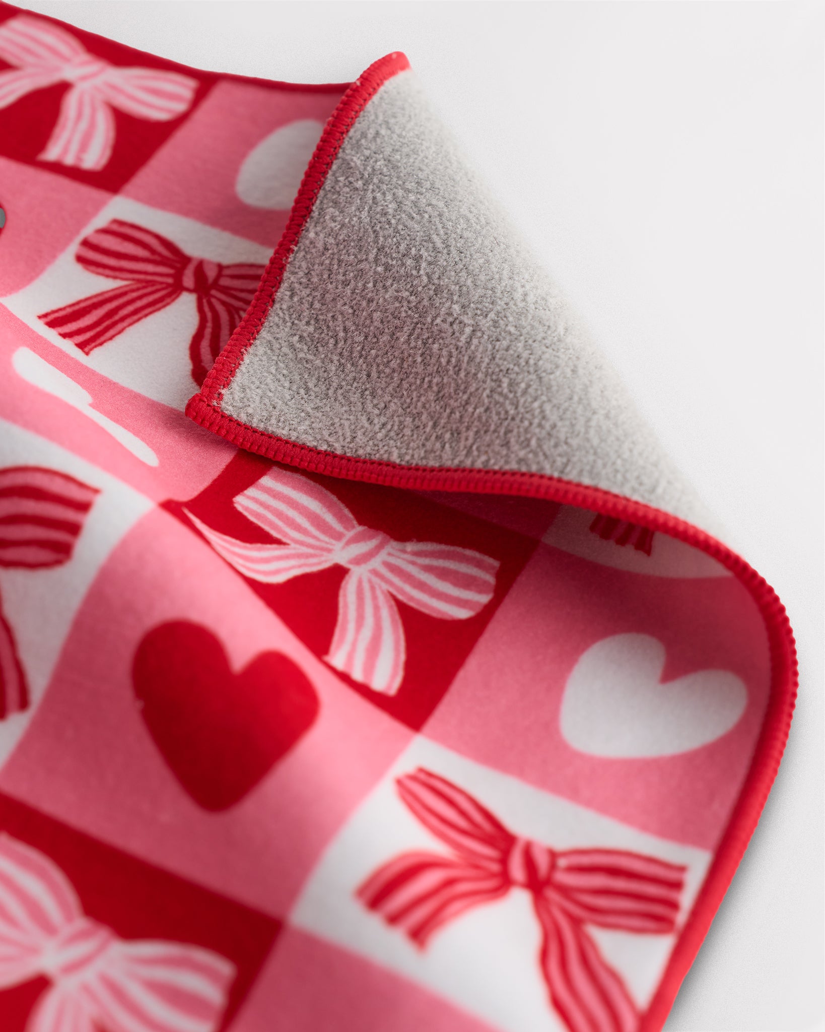 Close-up of multifunctional cloth with soft lining, red trim, and heart and bow print