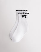 White kids socks with black ribbon bow, black lettuce-edge ruffle cuffs, and ribbed texture