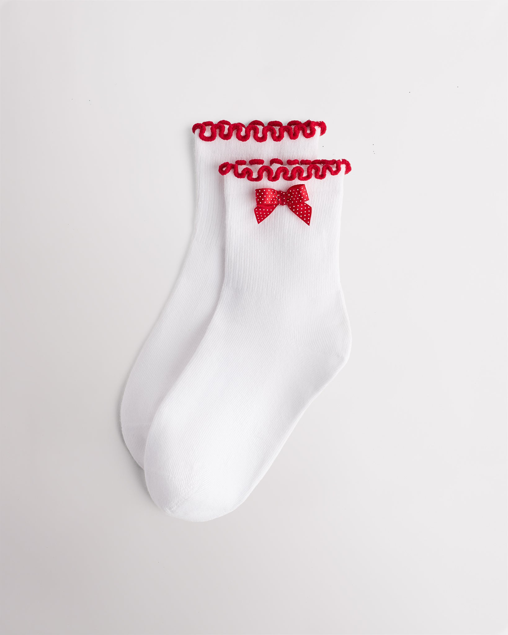White kids socks with red ribbon bow, red lettuce-edge ruffle cuffs, and ribbed texture