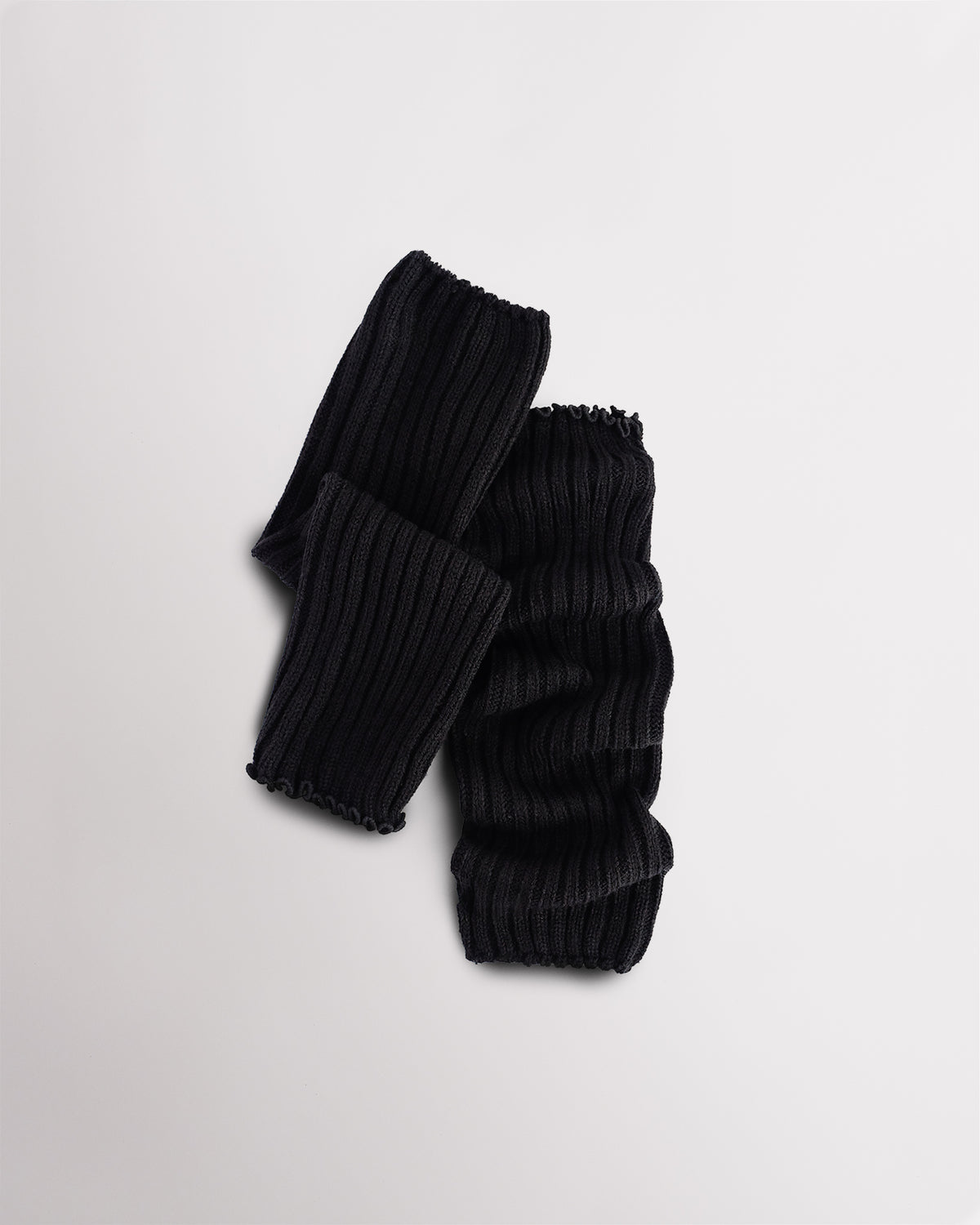 Black knit kids ballet leg warmers laid flat with a fitted shape and ribbed texture.