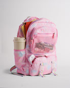 Pink Stelle backpack for kids packed with school and travel essentials, featuring side pocket, front mesh pocket, and zipper compartments.
