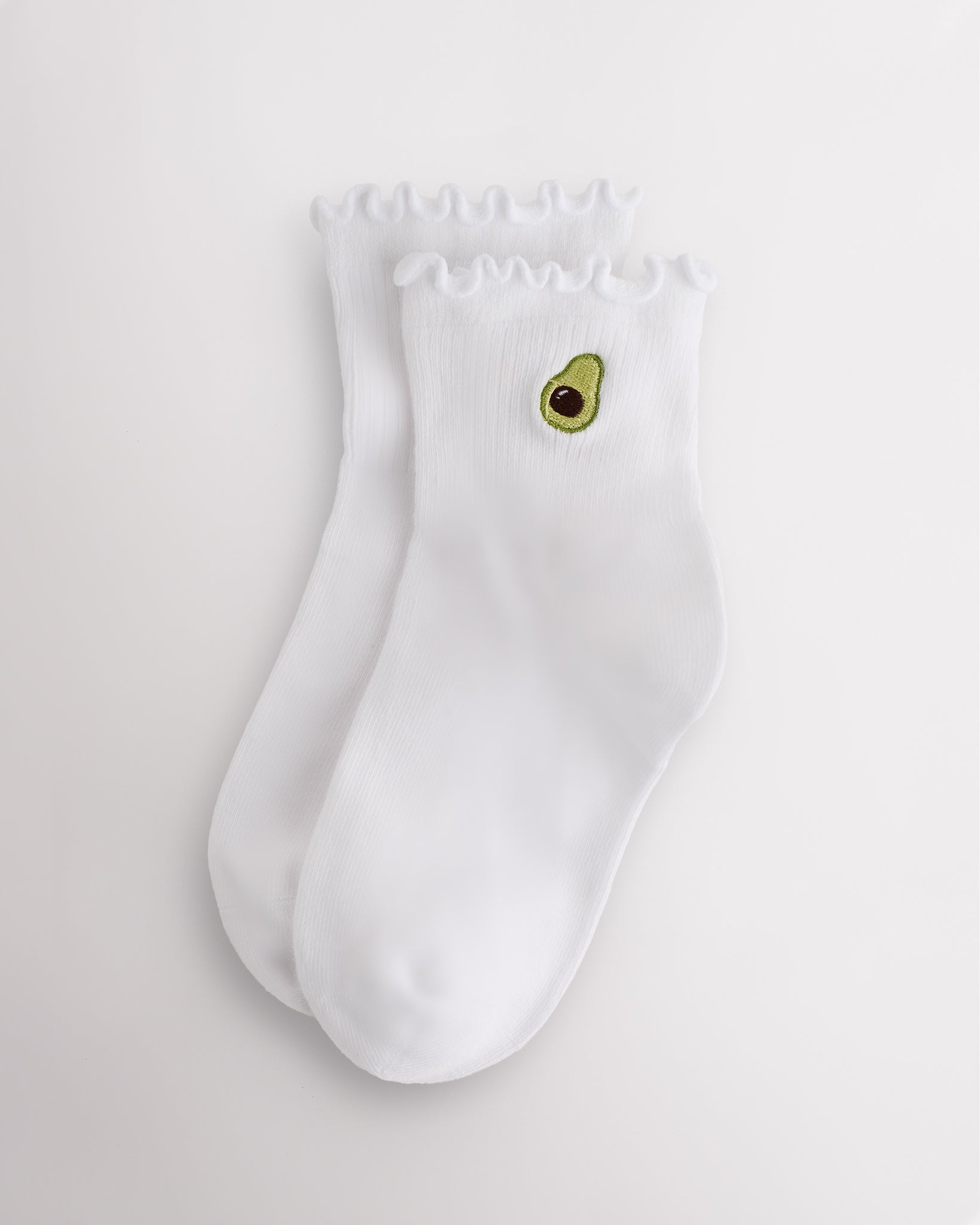 White kids ruffle socks with avocado embroidery, lettuce-edge trim, ribbed crew length, and soft everyday fit.