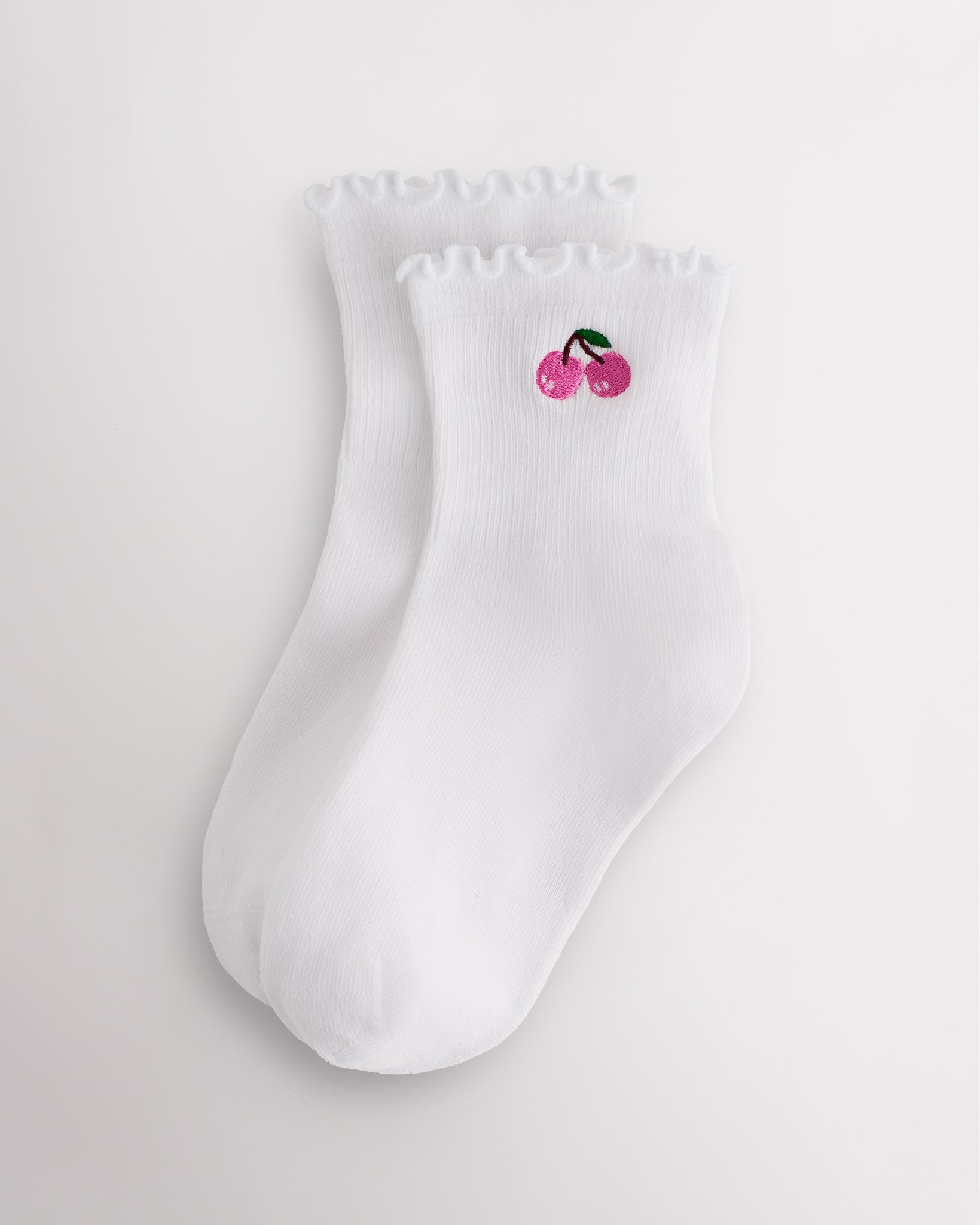 White kids ruffle socks with cherry embroidery, lettuce-edge trim, ribbed crew length, and shaped heel.