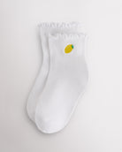 White kids ruffle socks with lemon embroidery, lettuce-edge trim, ribbed crew length, and soft ribbed fabric.