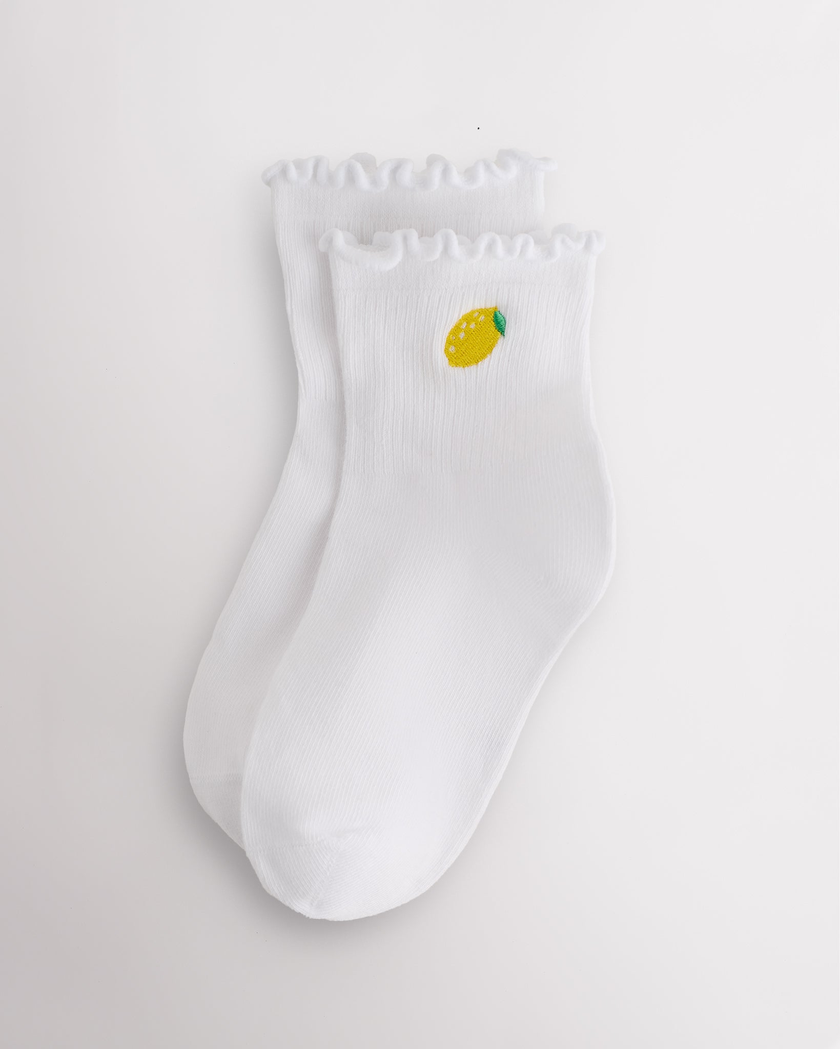 White kids ruffle socks with lemon embroidery, lettuce-edge trim, ribbed crew length, and soft ribbed fabric.