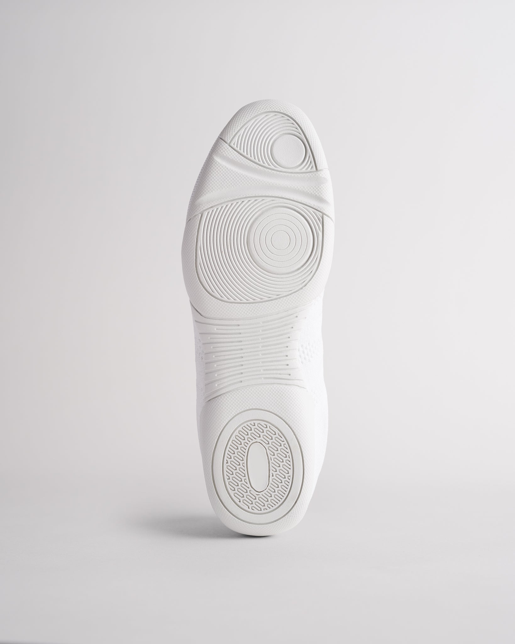 Bottom view of white cheer shoes showing textured sole with reliable traction pattern