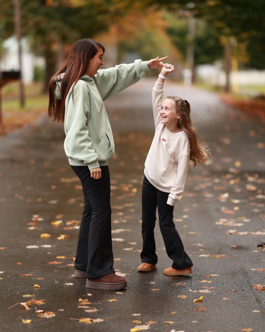 Two young girls playing on a path with fallen leaves
