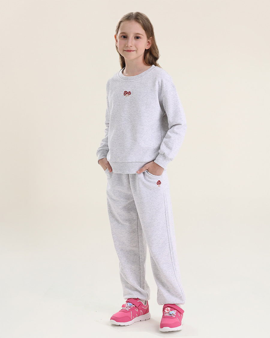 Girl wearing a gray tracksuit with pink shoes on a beige background