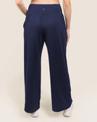 Navy blue wide-leg pants worn by a person on a beige background