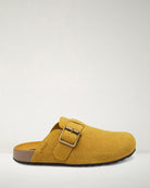 Yellow suede clog shoe with a buckle on a white background