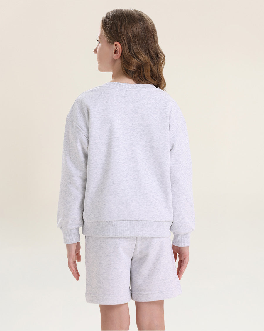 Person wearing a gray sweatshirt and shorts set on a beige background