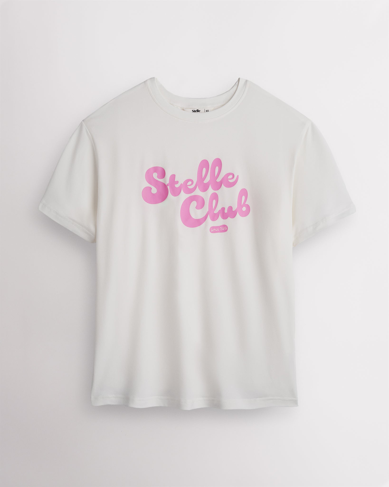 White Stelle oversized T-shirt with a pink Stelle Club graphic, laid flat on a grey background.