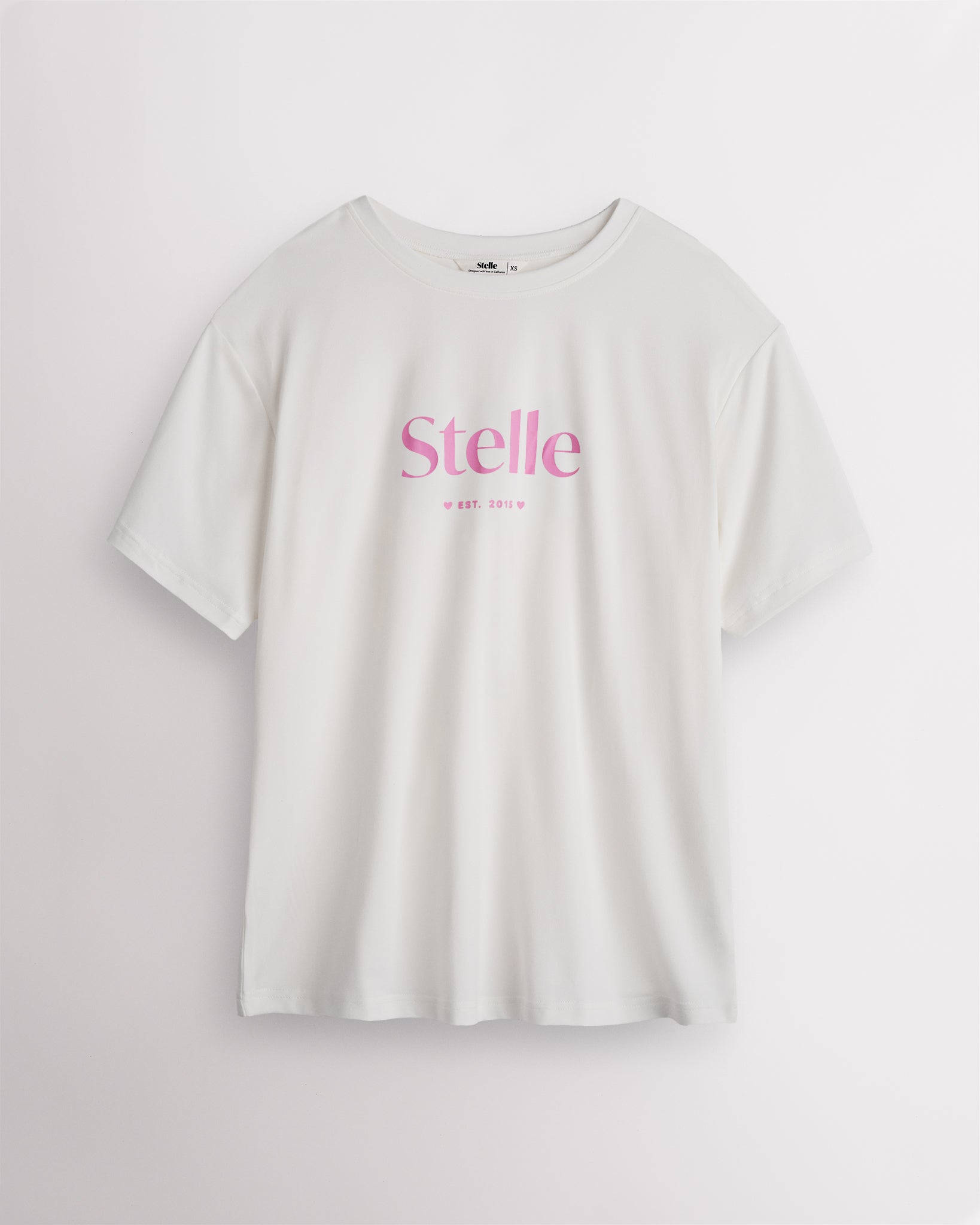 White Stelle oversized T-shirt with a pink Stelle logo on the chest, laid flat on a grey background.