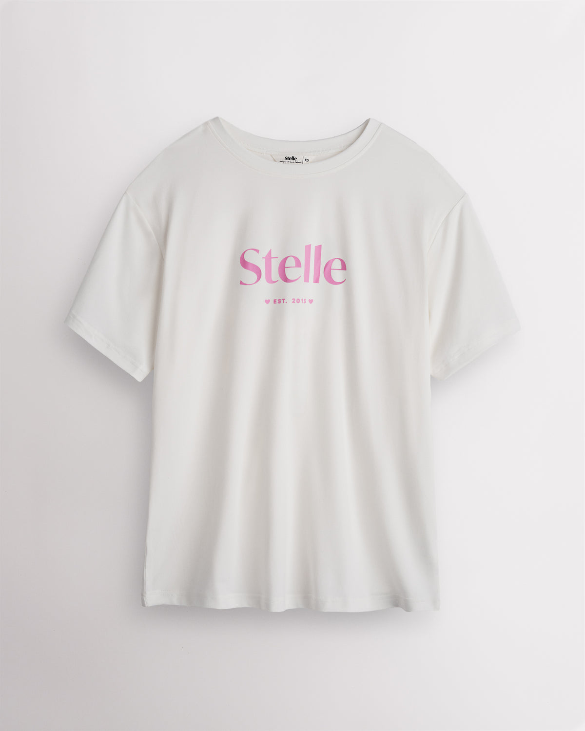 White Stelle oversized T-shirt with a pink Stelle logo on the chest, laid flat on a grey background.