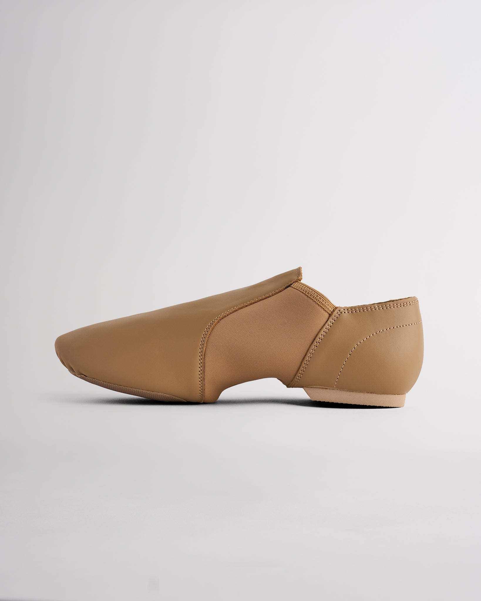 Side view of latte jazz dance shoe showing slip-on style, flexible neoprene arch, and low-profile split-sole construction.