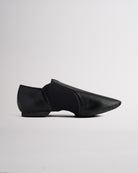 Side view of black vegan leather jazz shoe showing slip-on design, stitched details, and flexible dance shoe shape.