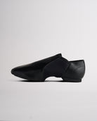 Side view of black vegan leather jazz shoe showing slip-on design, stitched details, and flexible dance shoe shape.