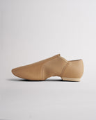 Side view of tan vegan leather jazz shoe showing slip-on design, stitched details, and flexible dance shoe shape.