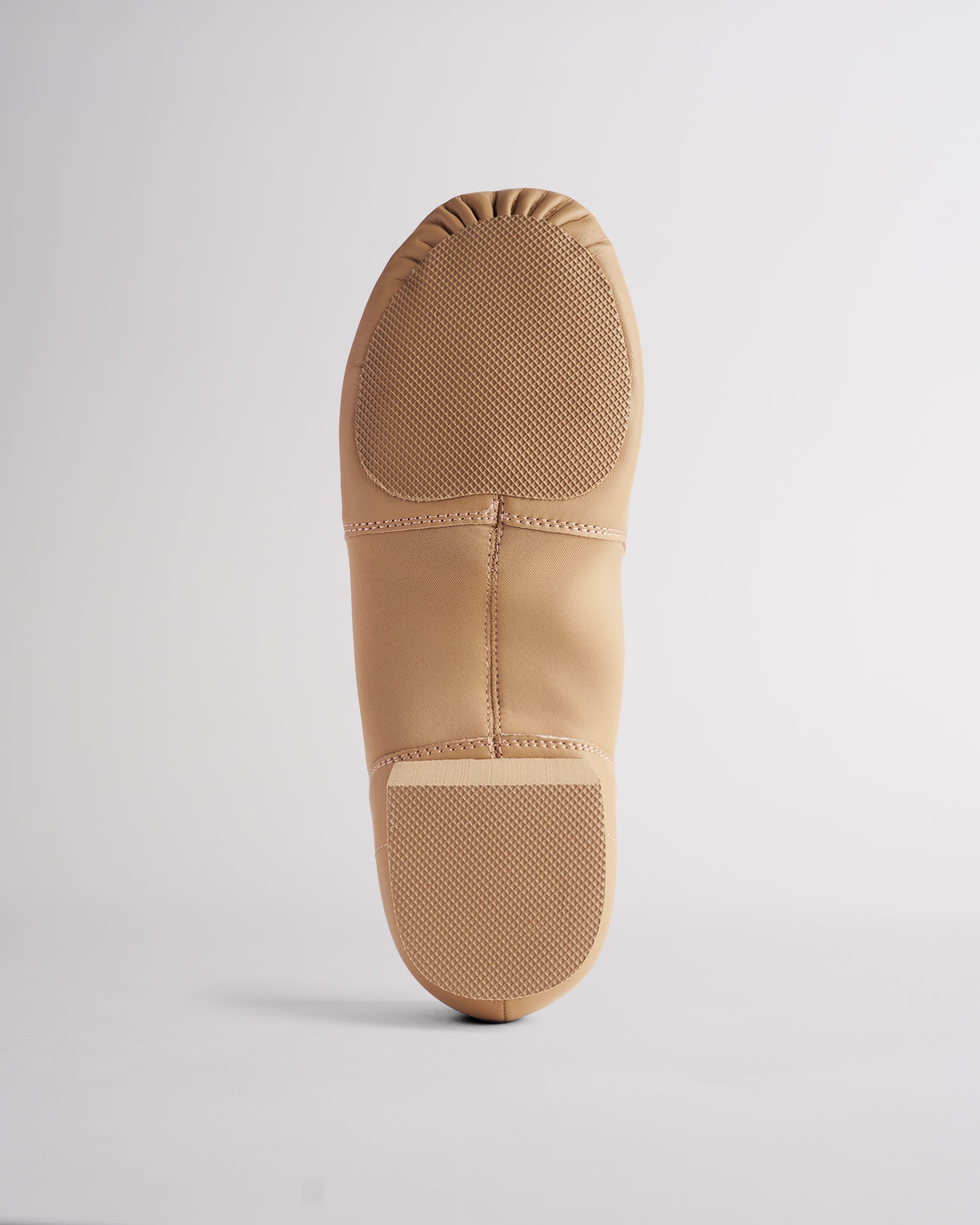 Sole view of tan adult jazz shoe showing anti-slip split sole and textured grip panels.