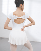 Back view of woman wearing a white dance leotard with twisted mesh detail and open-back silhouette.