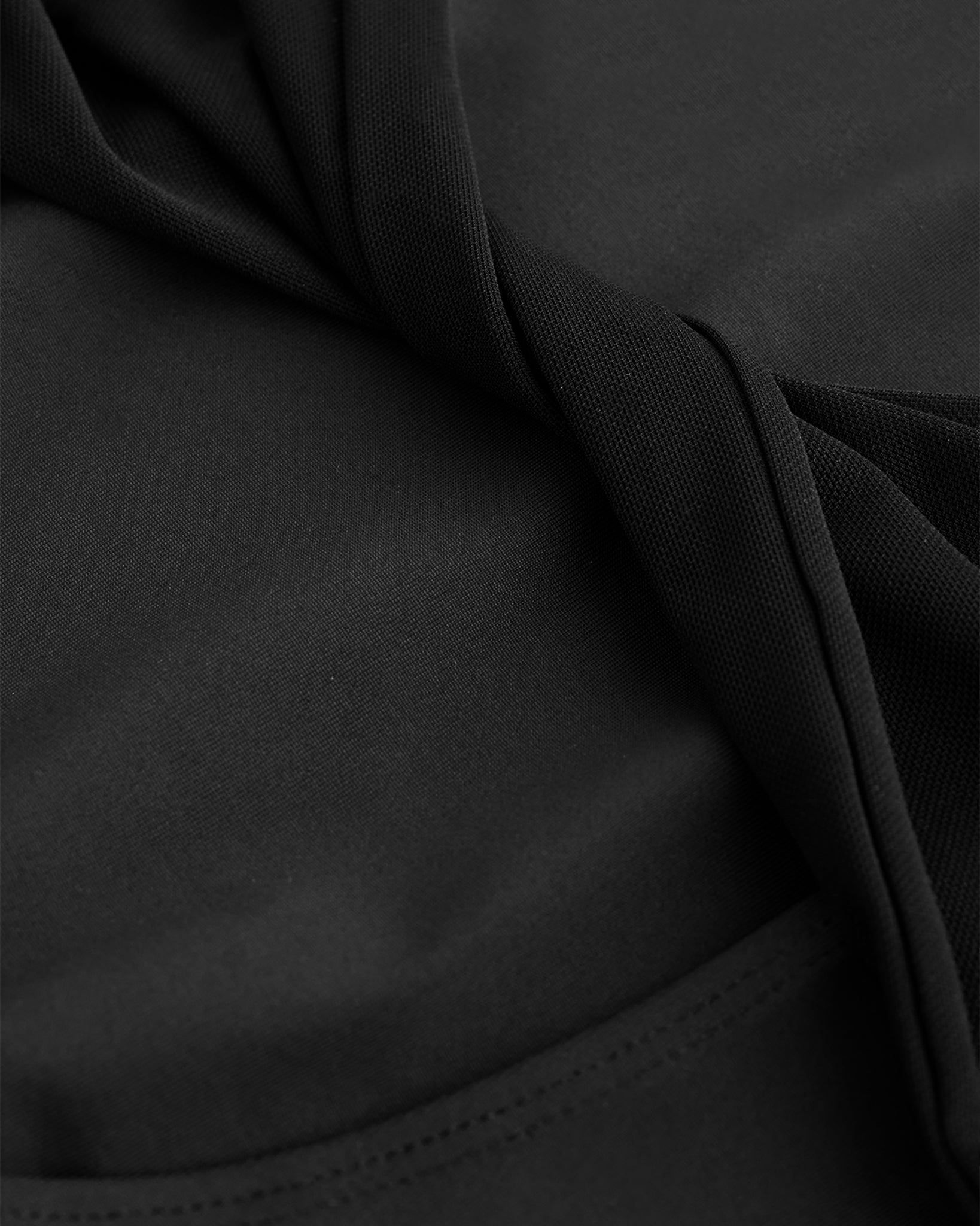 Close-up of Black performance leotard showing soft stretch fabric and twisted mesh back detail.