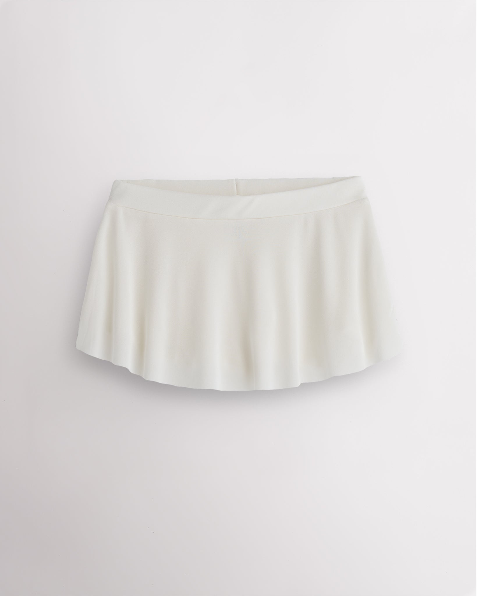 White pull on dance skirt with high-low hem, lightweight flowing fabric, and subtle shimmer finish for elegant movement
