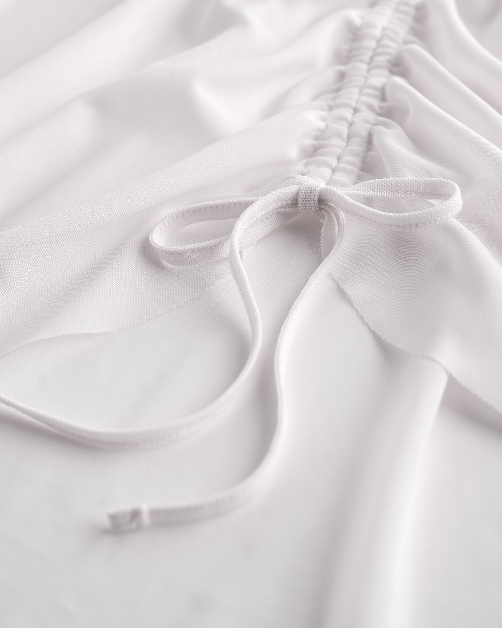 Close-up of white mesh ballet skirt showing adjustable ruched drawstring and soft sheer fabric.