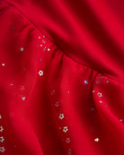 Close-up of red dance dress fabric with sparkling floral sequins on chiffon for a playful ballet performance look.