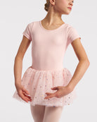 Girl wearing a ballet pink short sleeve tutu dance dress with multicolor celestial sequins, pink tights, and ballet shoes.