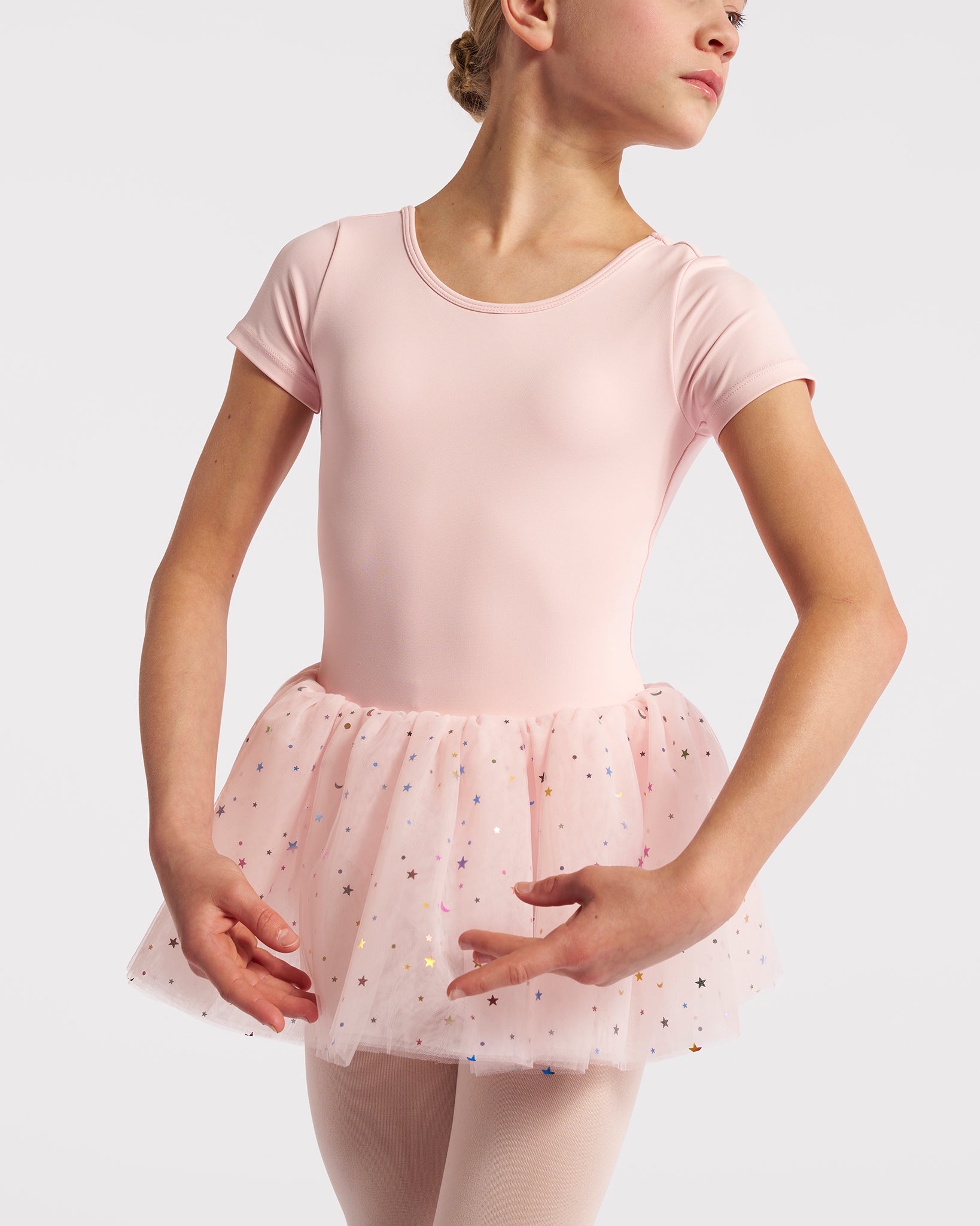 Girl wearing a ballet pink short sleeve tutu dance dress with multicolor celestial sequins, pink tights, and ballet shoes.