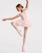 Young dancer wearing a ballet pink celestial sequin tutu dress while posing in ballet shoes and pink tights.