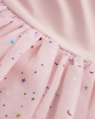 Close-up of ballet pink tutu dress skirt showing multicolor celestial sequins, layered mesh, and star and moon details.
