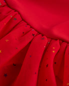 Close-up of red tutu dress skirt showing multicolor celestial sequins, layered mesh, and star and moon details.