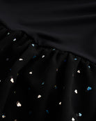 Close-up of black sequin dress showing heart-shaped sequins, chiffon skirt fabric, and gathered waist detail.