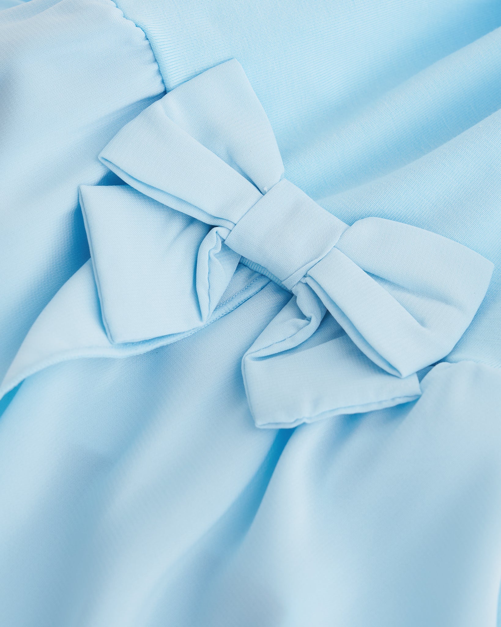 Close-up of blue ballet dress showing the decorative bow accent and soft chiffon wrap skirt.