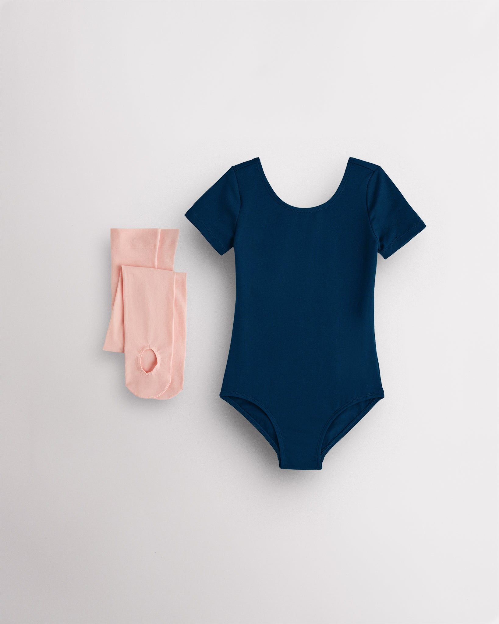 Navy short sleeve leotard with pink convertible dance tights laid flat for girls ballet and dance class.
