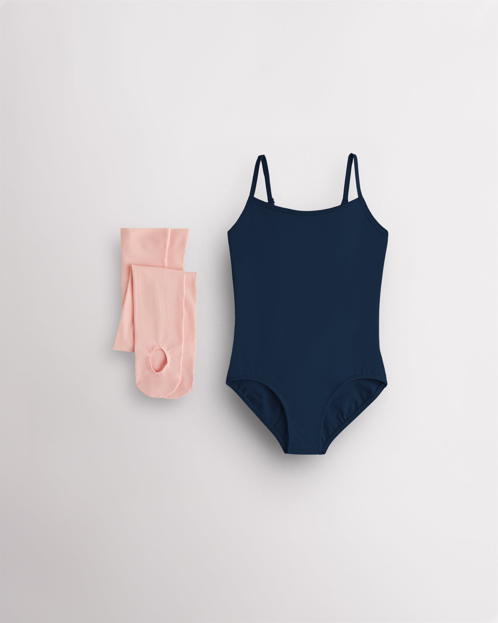 Navy girls camisole leotard with pink convertible dance tights laid flat for ballet and dance class.