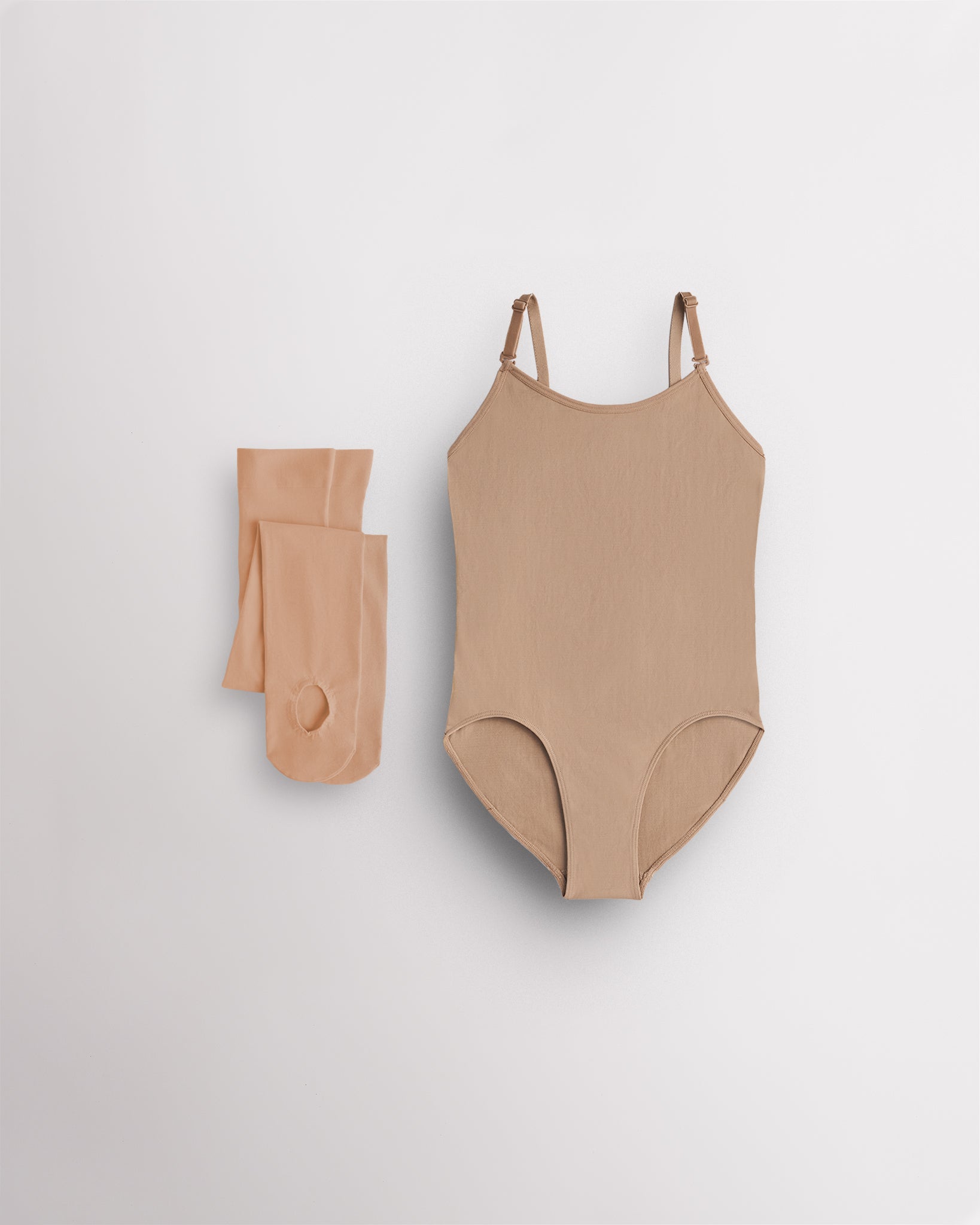 Nude camisole leotard for girls with tan convertible tights laid flat for ballet, dance, and costume layering.