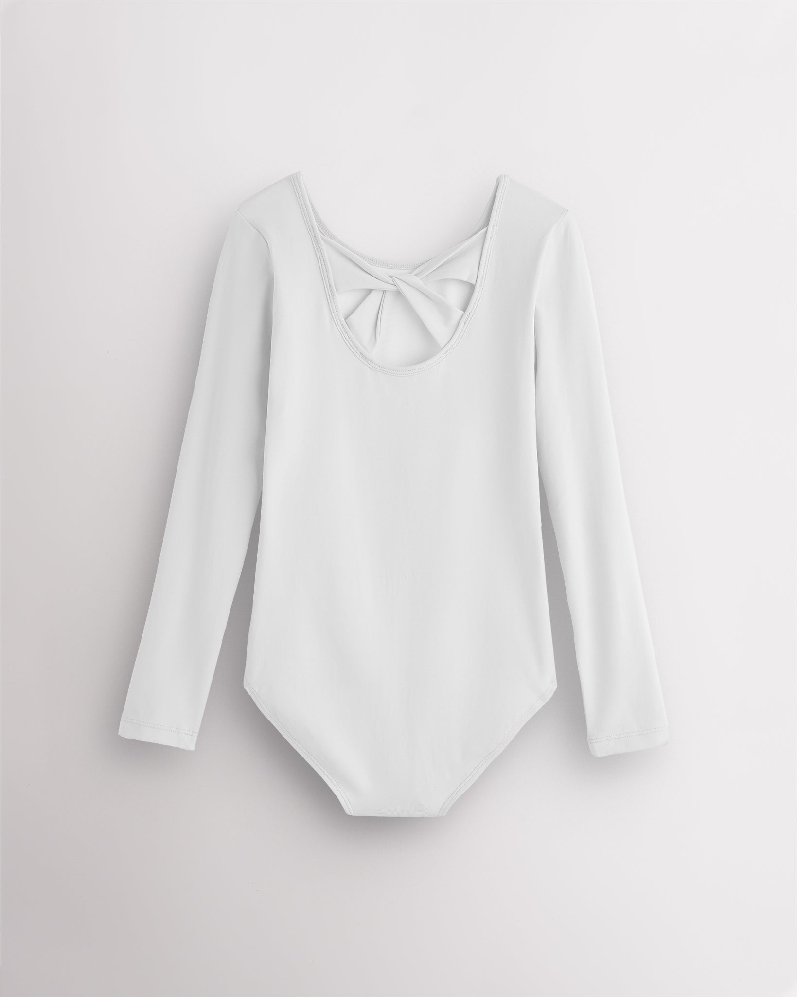 Back view of white long sleeve leotard for girls with twist-back bow detail and soft cotton fabric.