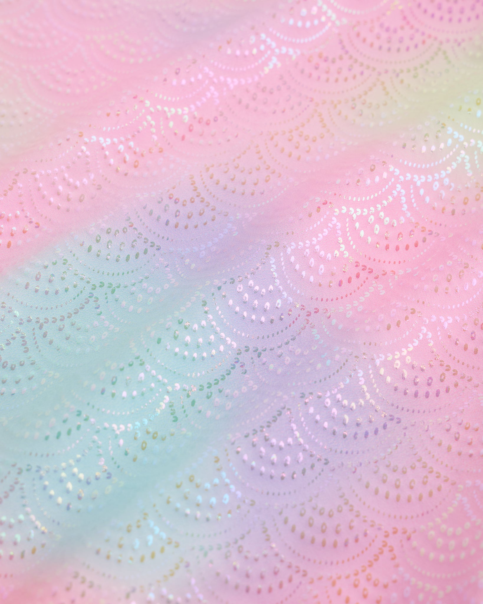 Close-up of Rainbow Mist girls unitard fabric showing butterflies, rainbows, moons, stars, and soft shimmer detail.