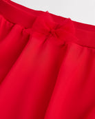 Close-up of a girls red chiffon ballet skirt showing the soft elastic waistband and delicate bow detail at the waist.