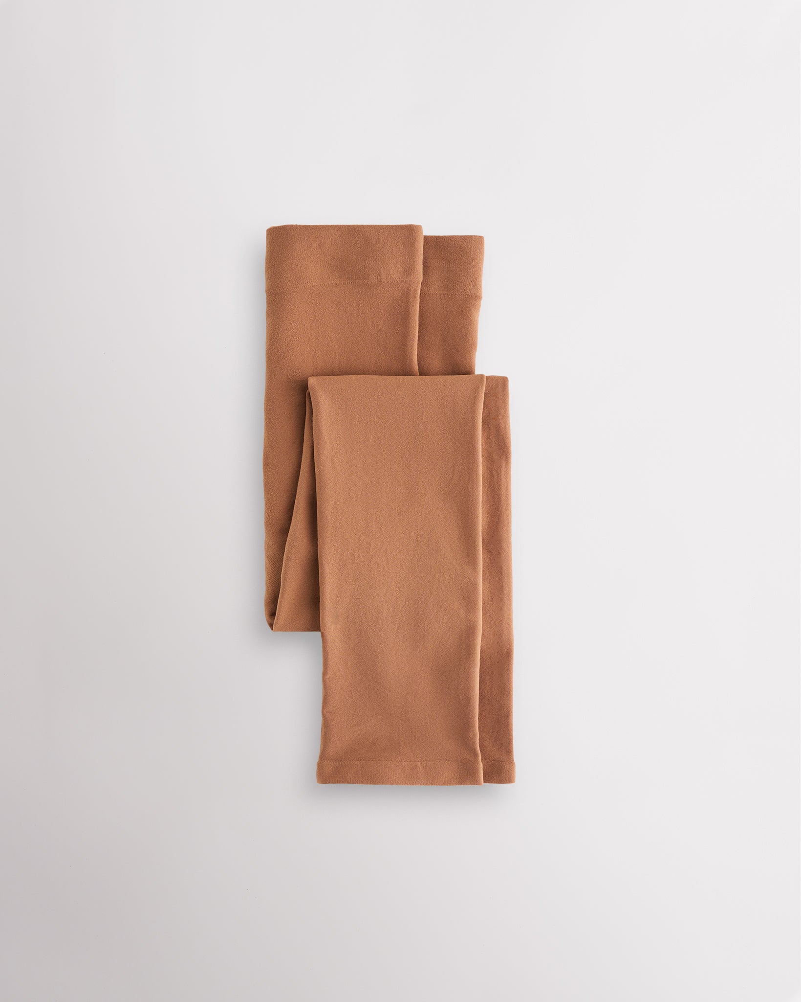 Warm Tan girls microfiber footless dance tights folded flat with elastic waistband and soft fabric for ballet and dance practice.